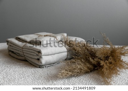 Linen is tied with twine against the background of a gray wall. Dried flowers as decoration. Focus point in the center, with blurry edges.