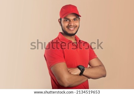 Portrait of a confident young delivery man standing with arms folded isolated over Color  background Royalty-Free Stock Photo #2134519653