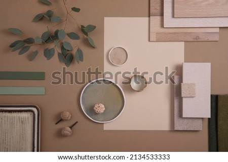 Creative flat lay composition of interior designer moodboard with textile and paint samples, panels and tiles. Beige, brown and green color palette. Copy space. Template. 