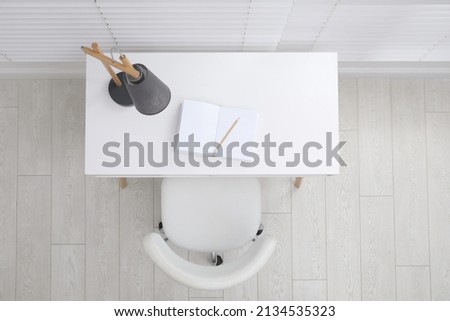 Stylish workplace with white desk and comfortable chair near window indoors, top view. Interior design Royalty-Free Stock Photo #2134535323