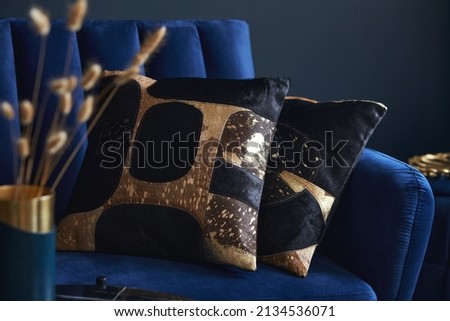Stylish close up on the elegant pillow in the glamour living room interior. Golden home decorations and creative personal accesories. Dark blue wall. Template. Copy space. Royalty-Free Stock Photo #2134536071