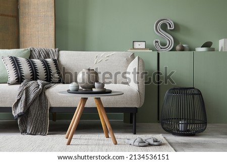 Modern living room interior composition with grey modern sofa, eucalyptus wooden commode, folding screen and modern home accessories. Sage green wall. Home staging. Template. Copy space. Royalty-Free Stock Photo #2134536151