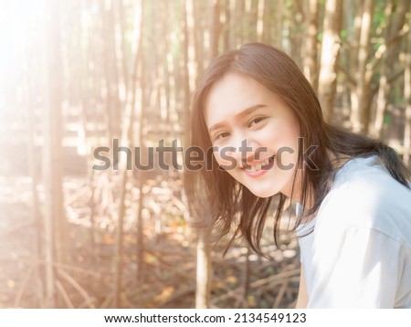 Smiling Asian women taking pictures while going on vacation. In the forest where the mangroves are densely covered with trees but when there is enough light to pass through it is perfect.