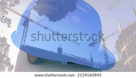 Image of safety helmet over building site and cranes. work and safety concept digitally generated image. Royalty-Free Stock Photo #2134560843