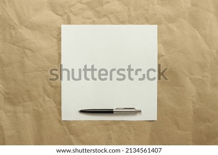 Square white empty sheet of paper with pen on a beige craft paper. Concept of analysis, study, attentive work. Stock photo with empty place for your text and design.
