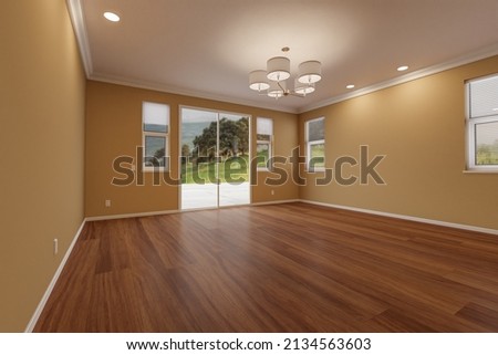 Newly Remodeled Room of House with Finished Wood Floors, Moulding, Dark Tan Paint and Ceiling Lights. Royalty-Free Stock Photo #2134563603