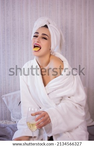 Beautiful girl with a towel on her head drinks wine.