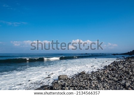 Coast with stones polished of sea water, in background a incoming  wave, horizon and a blue sky with some clouds, picture from Sao Vincente Madeira Portugal.