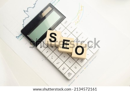 SEO word made up of wooden cubes on a white background between a black pen and a calculator. Business concept. High quality photo