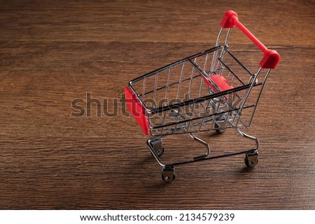 Empty grocery shopping cart on wooden background.