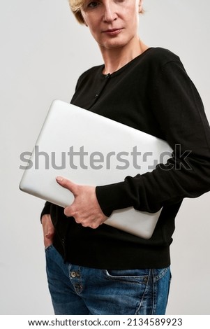 Cropped image of adult caucasian woman with laptop and hand in pocket looking away. Obscure face of blonde person. Concept of modern female lifestyle. Isolated on white background. Studio shoot