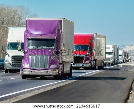 Horizontal shot of a multi-colored convoy of big trucks rolling down the interstate. Royalty-Free Stock Photo #2134615617