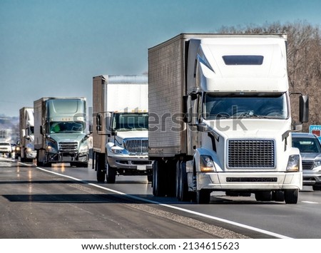 Horizontal shot of a convoy of eighteen wheeler turcks on an interstate highway. Royalty-Free Stock Photo #2134615623