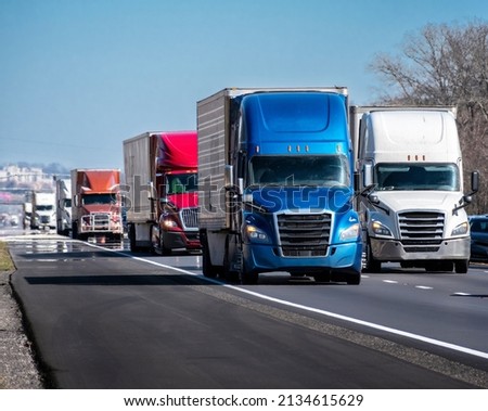 Horizontal shot of a long convoy of trucks on an interstate highway.

 Royalty-Free Stock Photo #2134615629