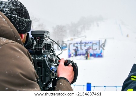 Camera operator film ski competition in ski resort in extreme snowy cold conditions