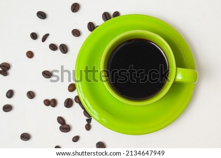 Black coffee and beans with mug on green on white background.