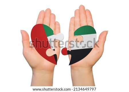 Woman hands are holding two parts of puzzle heart. National concept on white background. United Arab Emirates