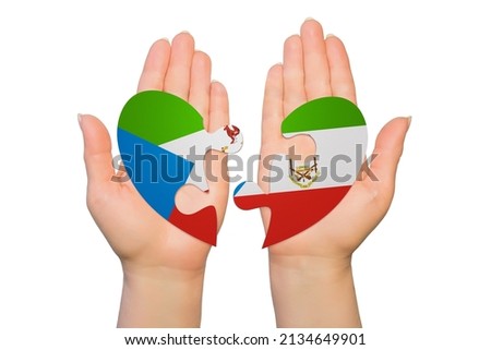Woman hands are holding two parts of puzzle heart. National concept on white background. Equatorial Guinea