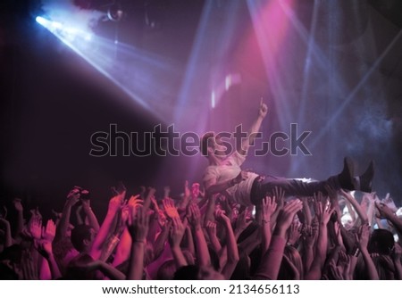 Surfing on a wave of praise. A stage diver being carried across the audience at a rock concert. Royalty-Free Stock Photo #2134656113