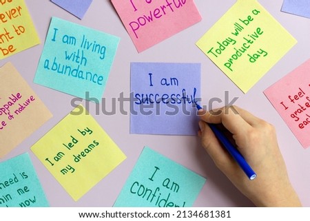 Positive affirmations concept. Man hand writing phrases of different colors sheets for notes on a pimk background. Motivational concept with handwritten text.  Royalty-Free Stock Photo #2134681381