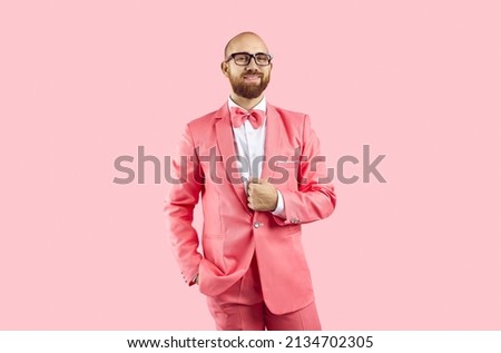 Portrait of young Caucasian man in suit and glasses isolated on pink studio background. Male performer and entertainer in fancy costume look at camera. Entertainment and party concept. Royalty-Free Stock Photo #2134702305