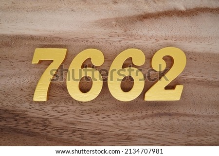 Wooden  numerals 7662 painted in gold on a dark brown and white patterned plank background.