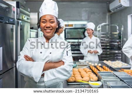 Smiling african  female bakers looking at camera..Chefs  baker in a chef dress and hat, cooking together in kitchen.Team of professional cooks in uniform preparing meals for a restaurant in   kitchen. Royalty-Free Stock Photo #2134710165