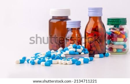 Several blue pill capsules were placed on a white background. and unlabeled pill bottles Royalty-Free Stock Photo #2134711221