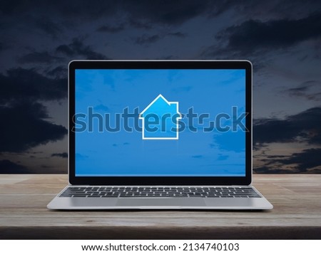 House icon with copy space on modern laptop computer monitor screen on wooden table over sunset sky, Business real estate online concept