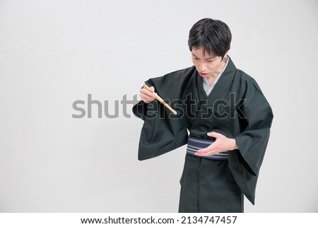 A rakugo storyteller who impersonates eating with a fan