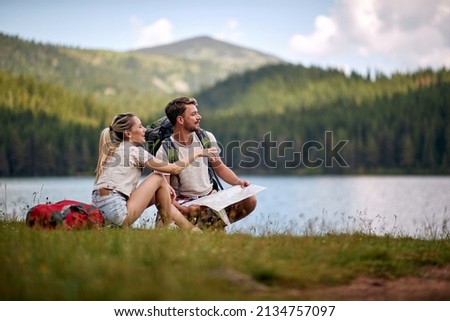Tourist couple with map looking at lake. Summer trip in nature. Lifestyle, togetherness, nature concept