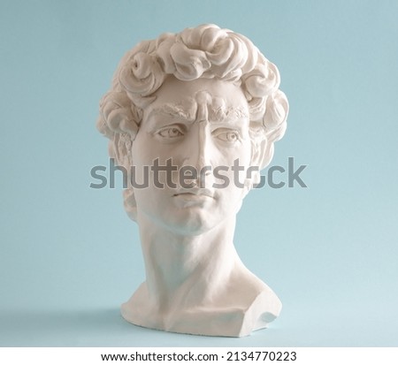 White plaster statue head of David on pastel blue background. Minimal art poster. Royalty-Free Stock Photo #2134770223