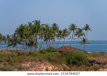 Red hut and coconut trees on beach against the clear blue sky
