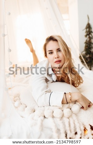 Stylish lady laying in canopy bed, smiling, relaxing, adorable woman chilling, enjoy weekends, spend winter holidays at home, New Year celebration, Christmas morning concept. High quality photo
