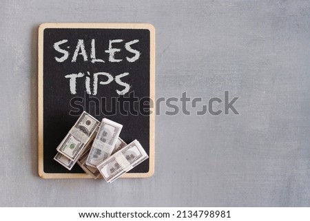 Top view image of banknotes and chalkboard with text SALES TIPS. Copy space. Business concept 