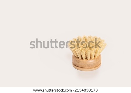 A natural bamboo dish brush on a light background. A zero waste, environmentally friendly alternative to plastic.