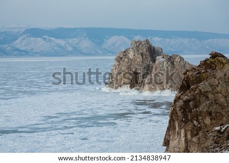 Baikal frozen lake and Shaman rock, Olkhon island, Burkhan cape. Clear ice and snow. Traveling in winter