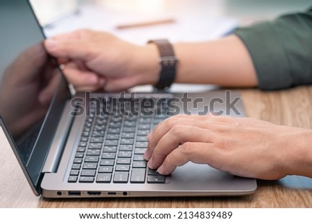 Close up hand a man typing on laptop keyboard on wood deck and document in a blur background business concept 