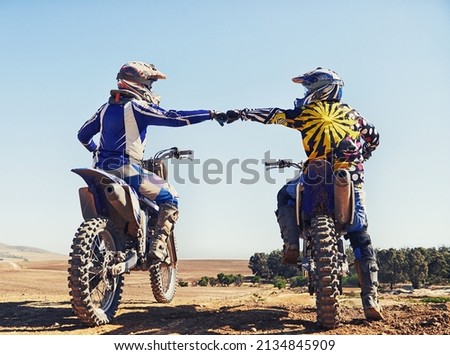 Time to rip up this track. Two motocross riders bumping fists before a race. Royalty-Free Stock Photo #2134845909
