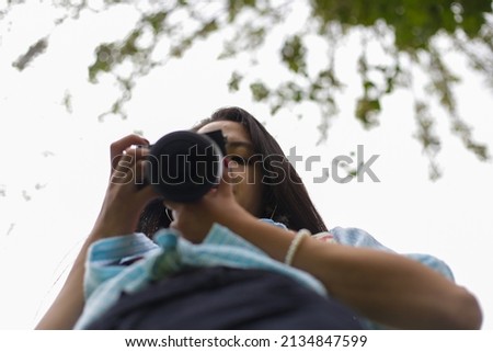 young woman photographing and reviewing her photos. Woman, student and photography concept.