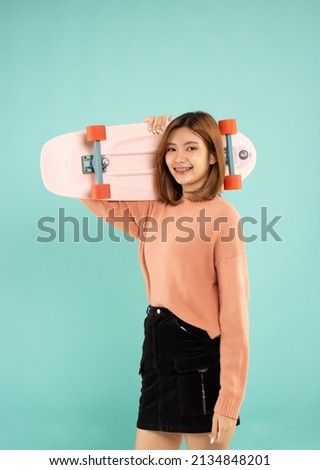 hipster girl holdind a pink skateboard and smile in studio