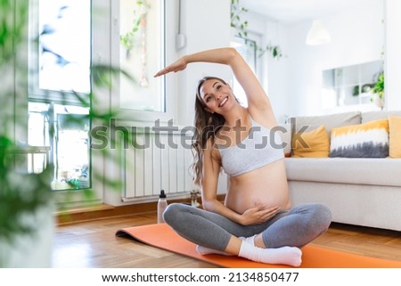 Portrait of young pregnant female working out at home. pregnant woman practicing yoga at home. Prenatal groins stretch. Buddha Konasana Pose. Pregnancy yoga and fitness.