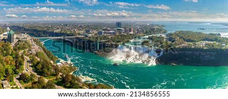 Panorama of aerial view of Canadian side view of Niagara Falls, American Falls and Rainbow International Bridge in Niagara Falls, Ontario, Canada Royalty-Free Stock Photo #2134856555