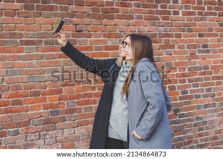 Two hipster girlfriends taking a self photo for social networks in urban city background - friendship concept.