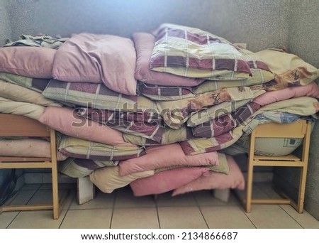 Many pillows are stacked on the chairs. Humanitarian aid. Shelter for refugees. Lviv, Ukraine. Multi-colored objects for sleep. Interior.