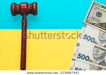 Judicial gavel with hryvnia money on a yellow-blue background of the colors of the flag of Ukraine.