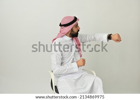 Happy Saudi Arab man smart watch paying Contactless or purchasing and shopping wearing traditional dress using digital technology 