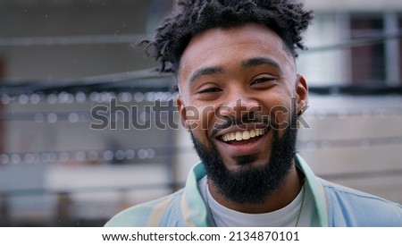 A happy young Brazilian man standing outside in drizzle smiling at camera Royalty-Free Stock Photo #2134870101