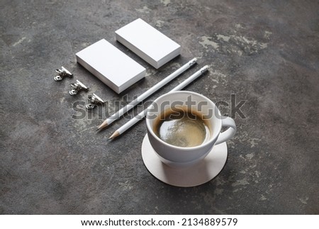 Photo of coffee cup and blank stationery set on concrete background. Objects for placing your design.