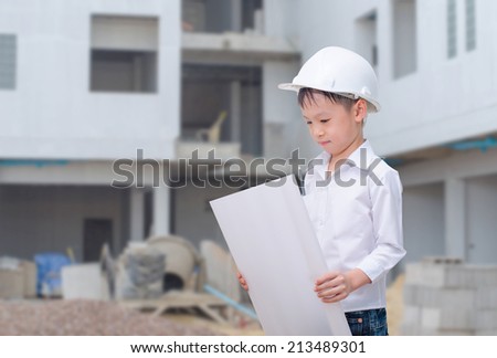 building, developing, construction and architecture concept - little Asian boy with white helmet and blueprint.